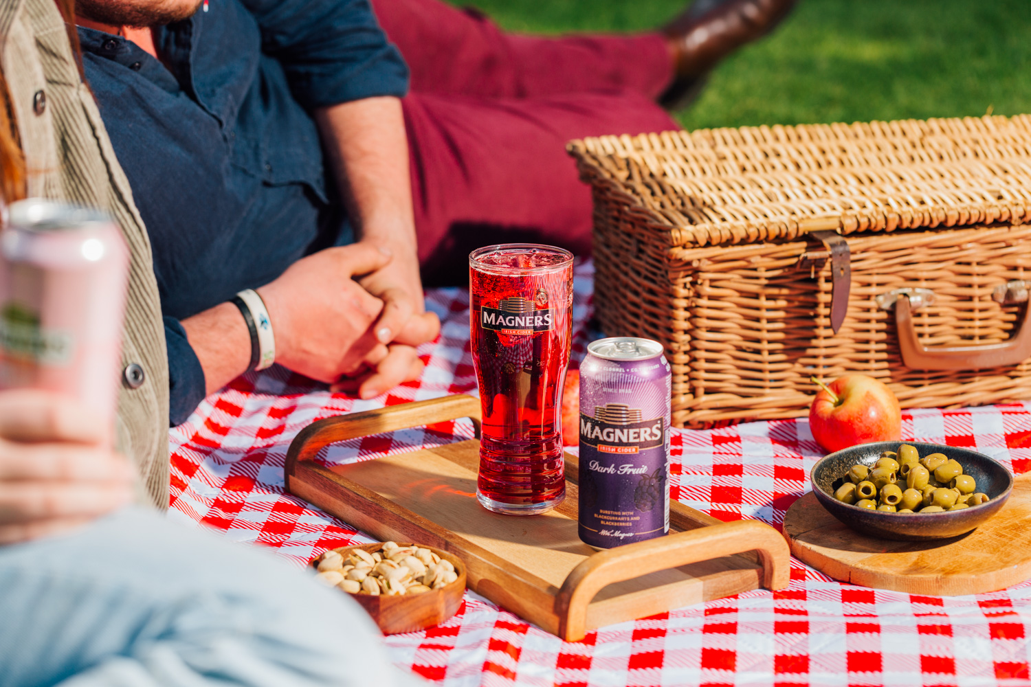 Two people enjoying a glass of Magners Dark fruit on a picnic blanket